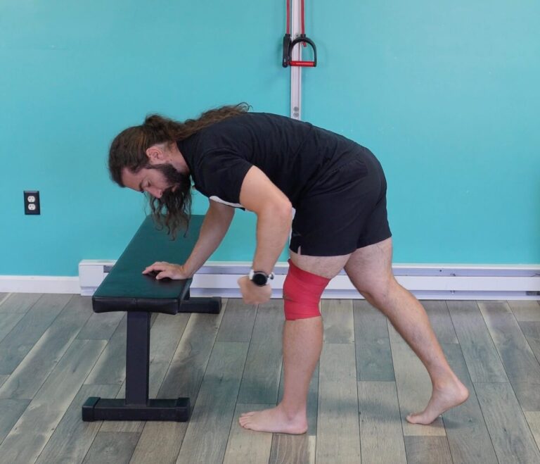 Dr. John with muscle floss wrapped around above and below his knee cap to demonstrate how to do the dynamic hamstring exercise with muscle floss